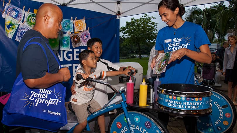 Child riding blender bike at a community fair